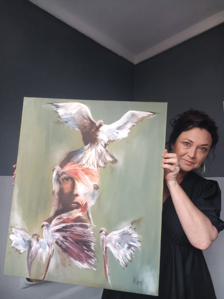 Kim Bezuidenhout in her studio holding Kim with the Doves Painting