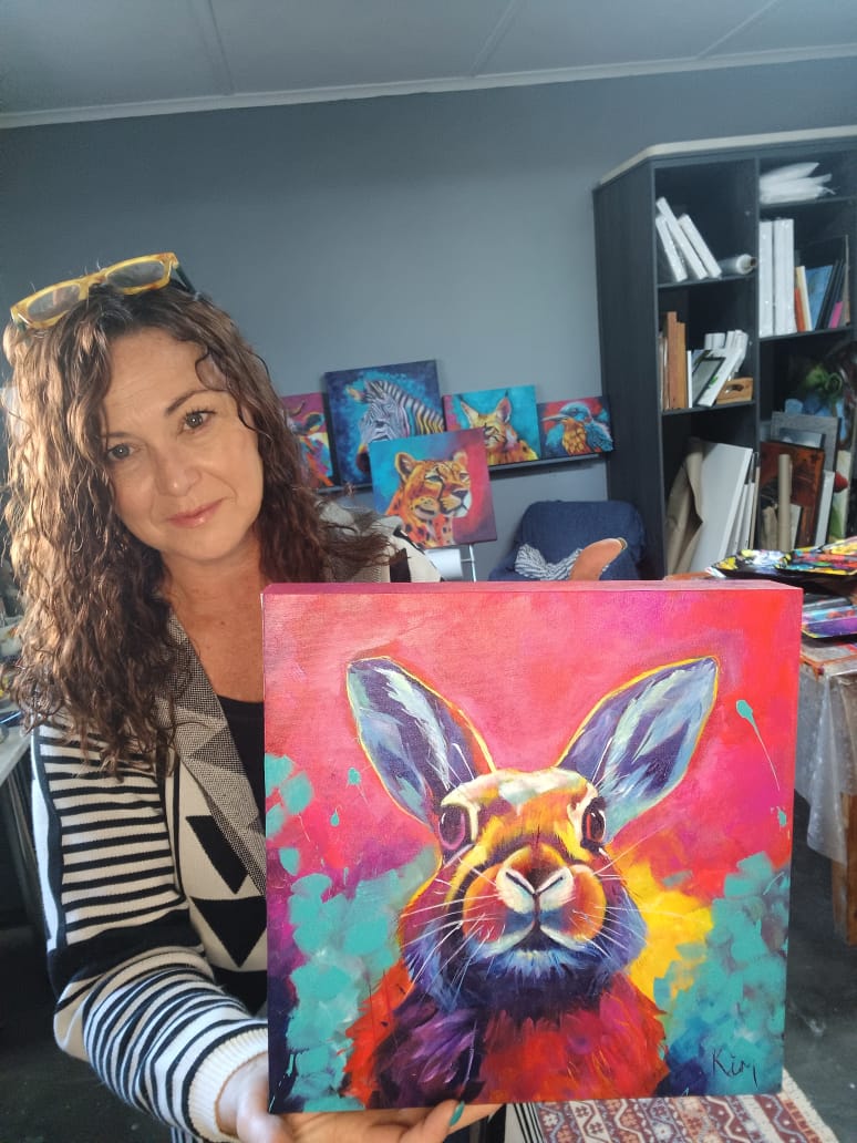 Kim Bezuidenhout in her studio holding Kim with the Rabbit Painting