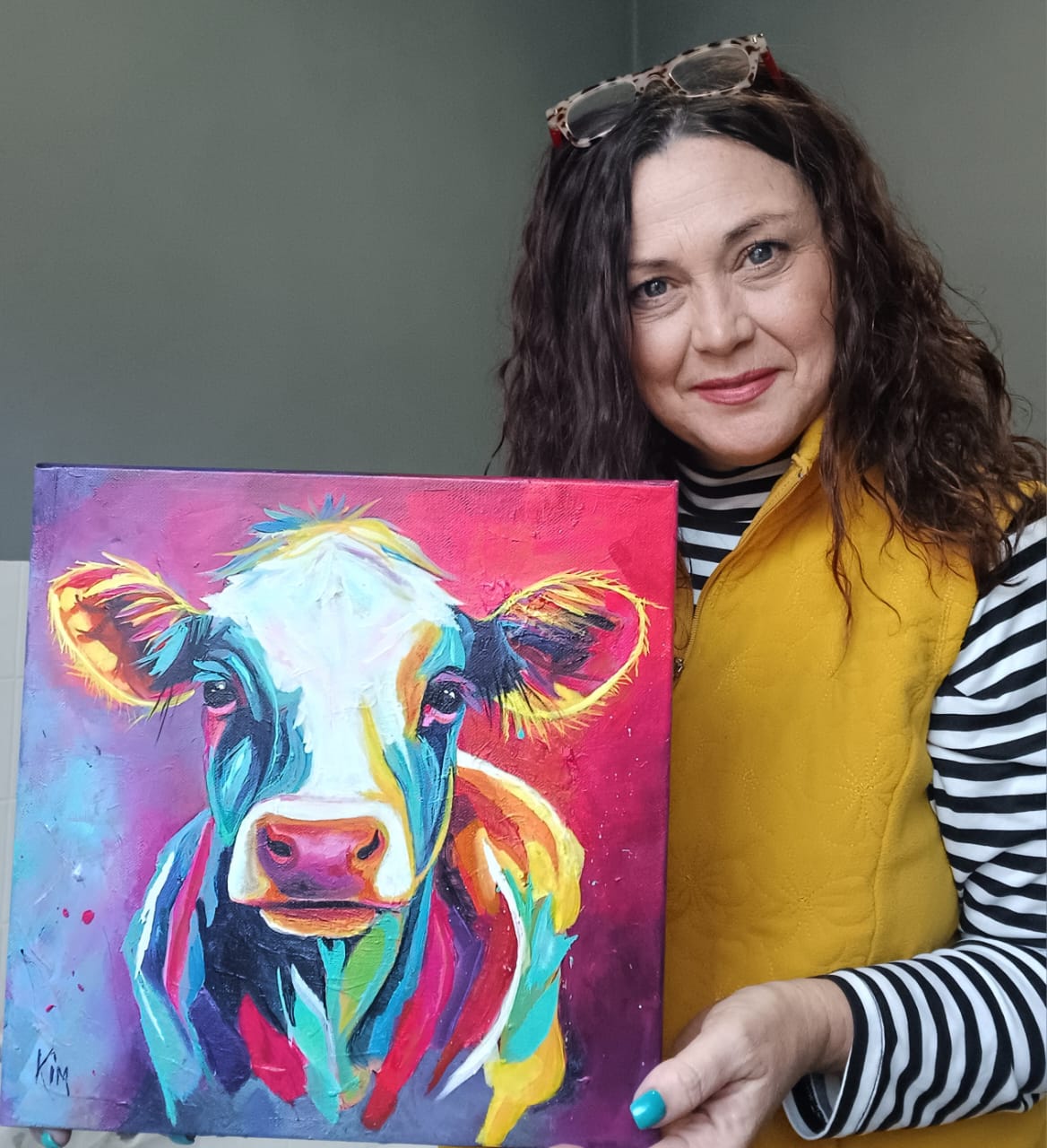 Kim Bezuidenhout in her studio holding Kim with the Red Cow Painting