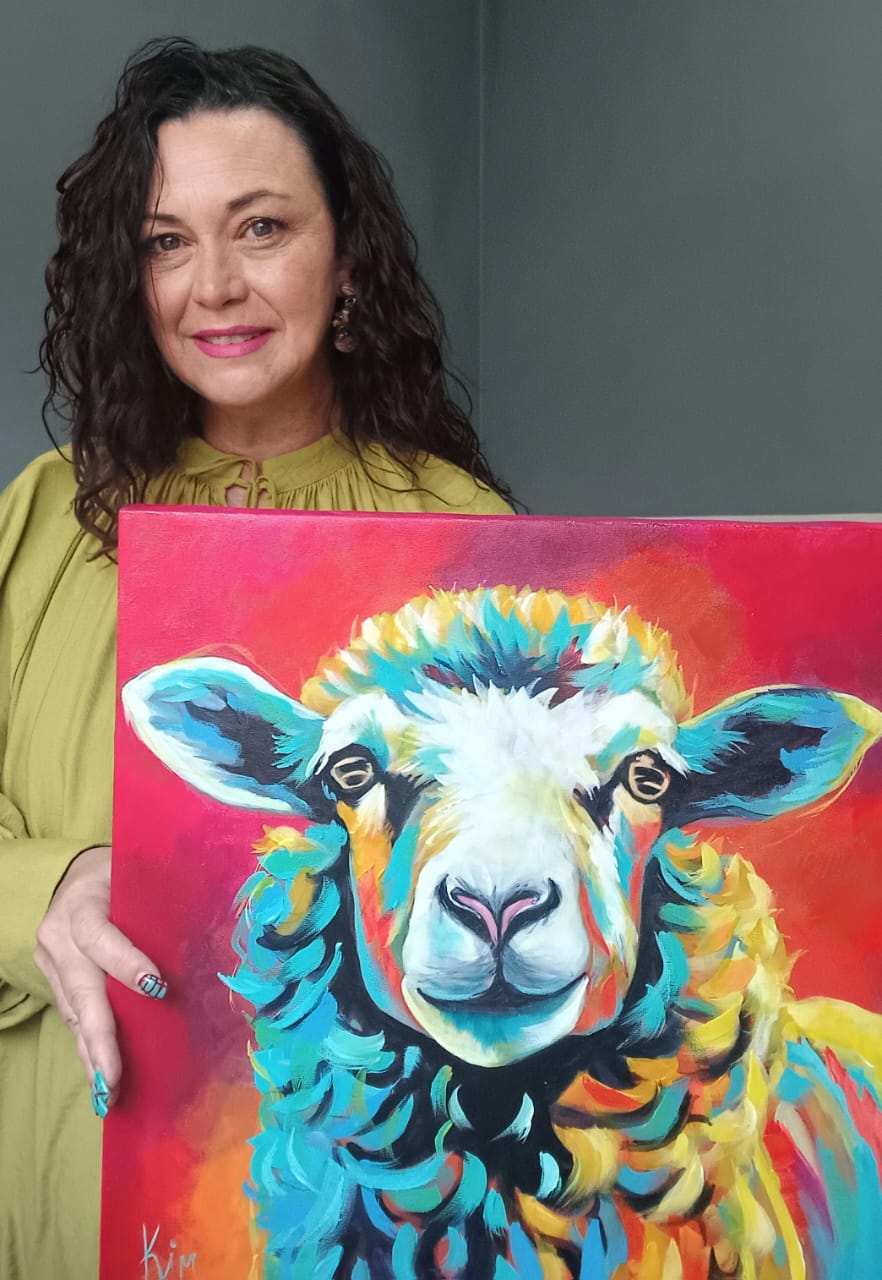 Kim Bezuidenhout in her studio holding Kim with the Sheep Painting
